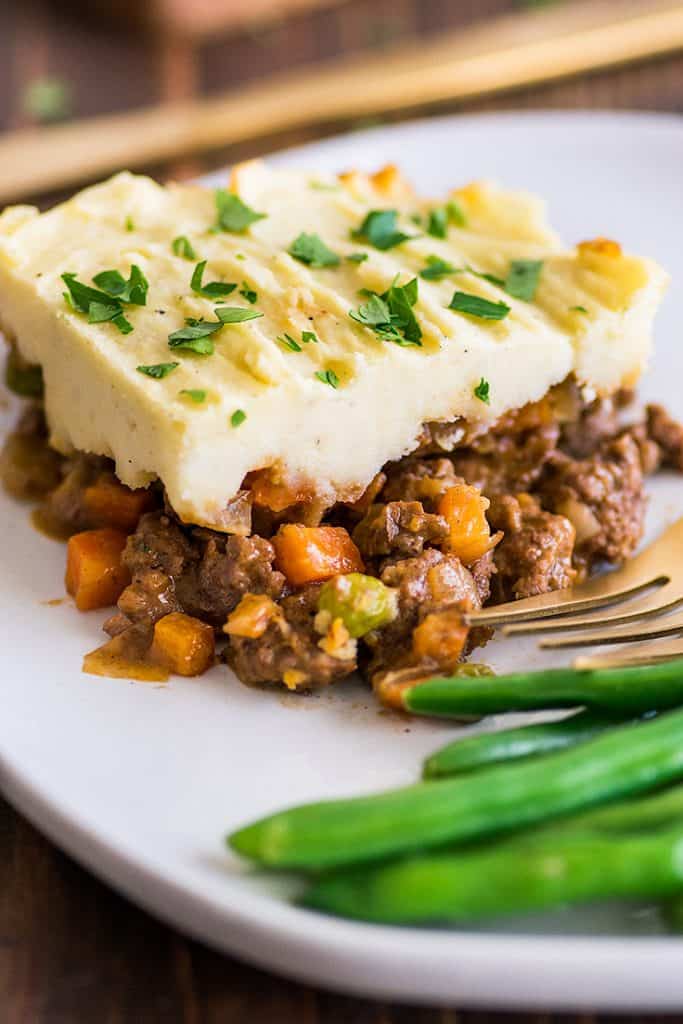 This Easy Shepherd's Pie With Ground Beef recipe is a perfect easy dinner for two or three people. | #dinnerfortwo | #easydinner | #shepherdspie | #groundbeef | Picture of a slice of Easy Shepherd's Pie With Ground Beef on a white plate.