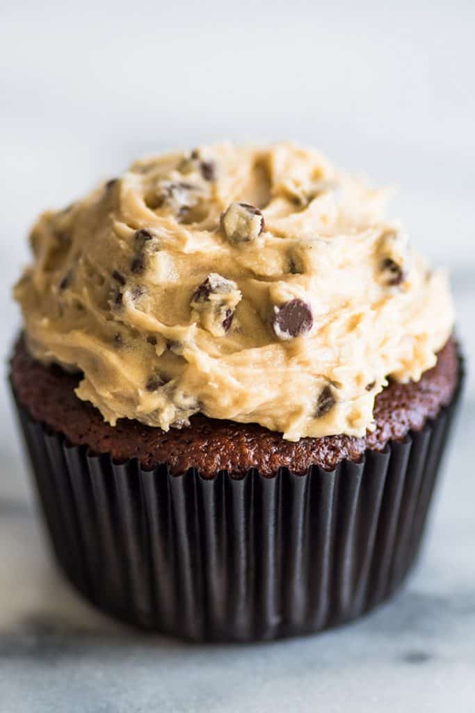 This Small-batch Cookie Dough Frosting tastes just like an extra creamy batch of cookie dough that you happen to get to spread over a cupcake. | #frosting | #cookiedough | #smallbatch | Photo of Small-batch Cookie Dough Frosting on a chocolate cupcake.