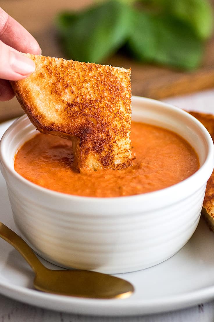 Picture of grilled cheese sandwich being dipped in Creamy Tomato Soup Recipe for Two.