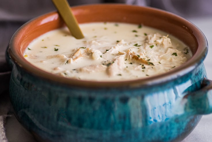 This easy Keto Chicken and "Rice" Soup is rich, creamy, and the BEST keto comfort food. | #keto | #cauliflowerrice | #ketorecipe | Wide photo of Keto Chicken Soup in blue bowl with a gold spoon.
