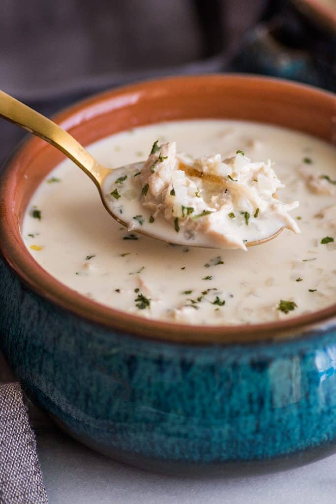 This easy Keto Chicken and "Rice" Soup is rich, creamy, and the BEST keto comfort food. | #keto | #cauliflowerrice | #ketorecipe | Photo of Keto Chicken Soup in blue bowl with a spoonful of soup.