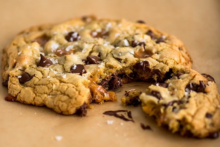 One Giant Chocolate Chip Cookie for Two, made three different ways, classic, caramel and sea salt, and triple chocolate. | #cookies | #chocolatechipcookies | #giantcookie | Photo of One Caramel and Sea Salt Chocolate Chip Cookie for Two on parchment paper.