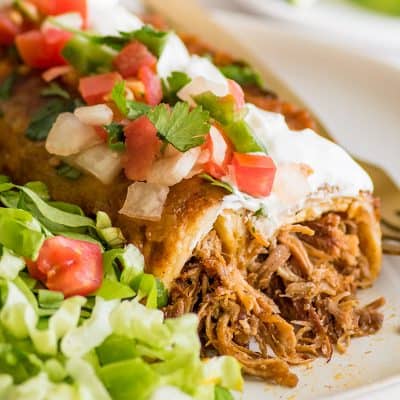 Picture of carnitas enchiladas with pulled pork, sour cream, and pico de gallo.