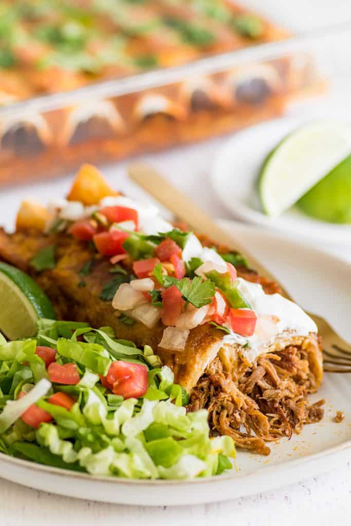 Picture of carnitas enchiladas with pulled pork, sour cream, and pico de gallo.