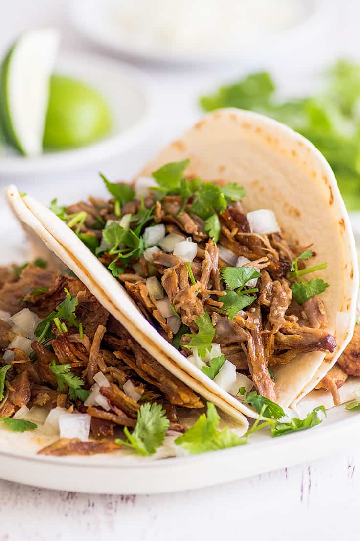 Picture of carnitas made into tacos with cilantro and onion.