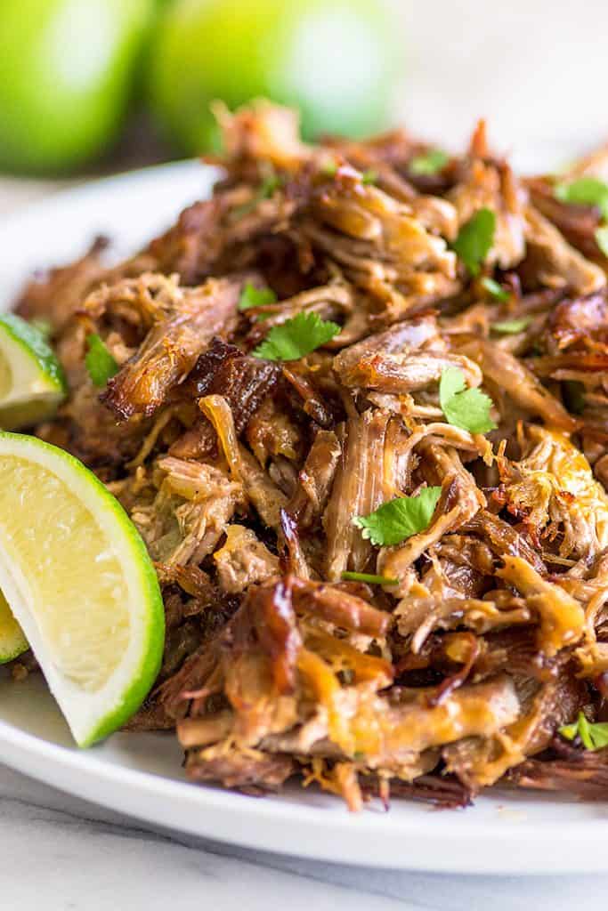 Photo of easy carnitas on a plate with limes.