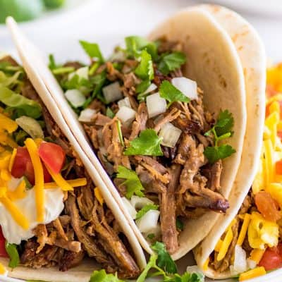 Three different types of carnitas tacos on a plate.