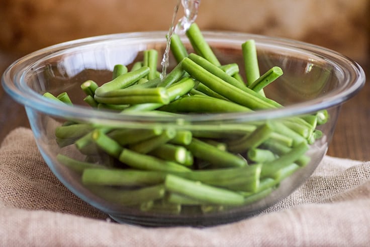 Image of How to Steam Green Beans in the Microwave step 1, water being poured over green beans.