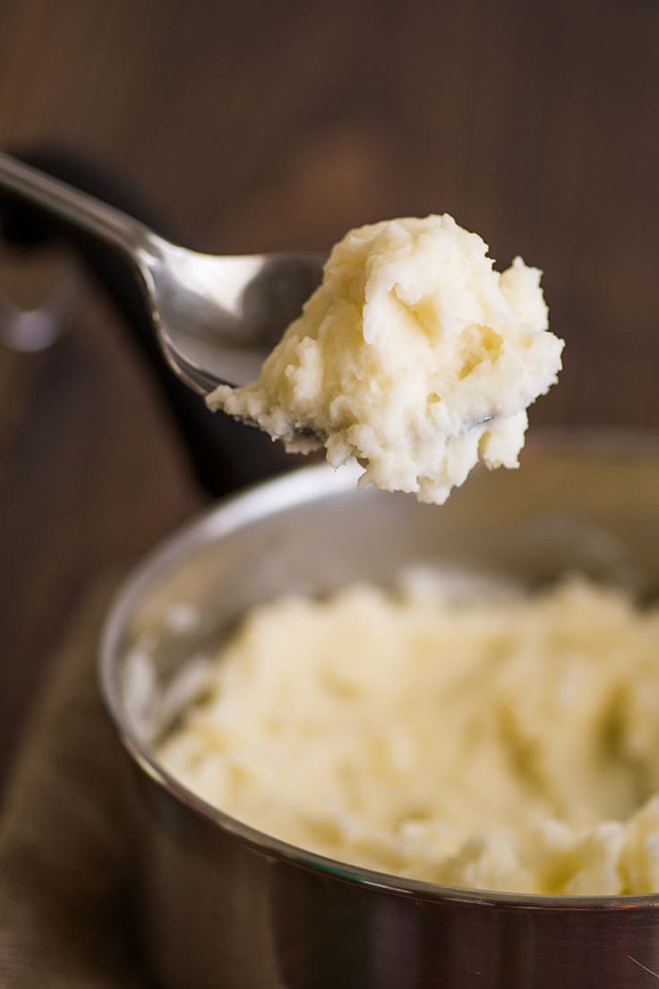 Simple and easy Mashed Potatoes for Two made with one pot and one potato for a quick and easy side dish. | #sidedish | #easy | #recipefortwo | Mashed Potatoes for Two in a pot with a spoonful of potatoes scooped out.