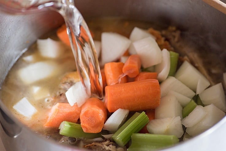 Chicken Carcass Soup Step 3, vegetables and water being added to soup.