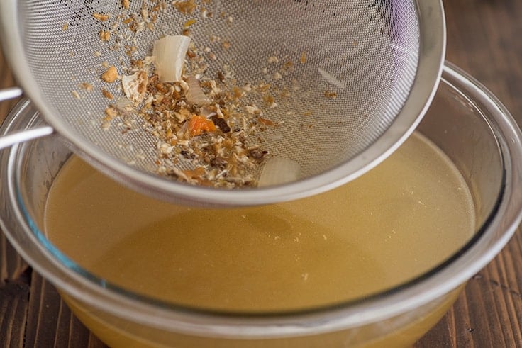 Chicken Carcass Soup Step 5: broth being strained through fine-mesh strainer.