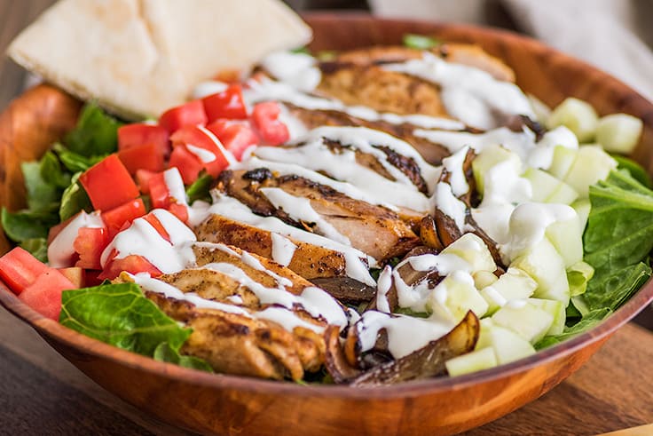 Chicken Shawarma Salad in a bowl drizzled with yogurt dressing.