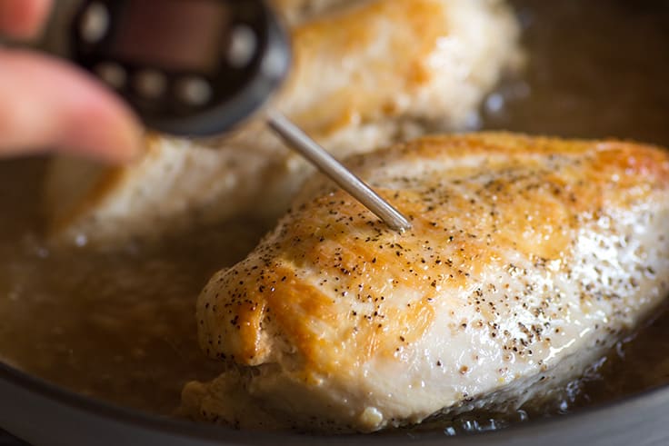 Thermometer checking the temperature of chicken breasts.