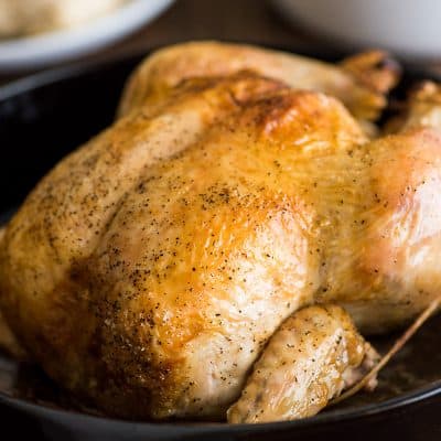 Feature image of a whole roasted chicken in a cast iron pan.
