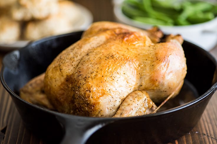 Photo of a whole roasted chicken cooked in a cast iron pan.