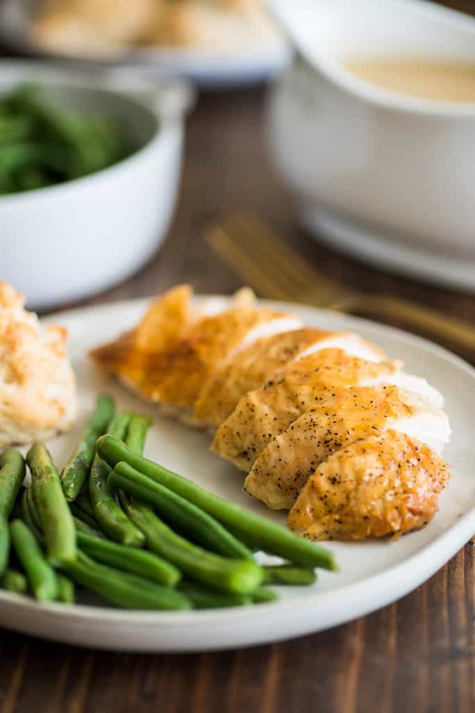 Roasted chicken breast sliced on a plate with green beans.