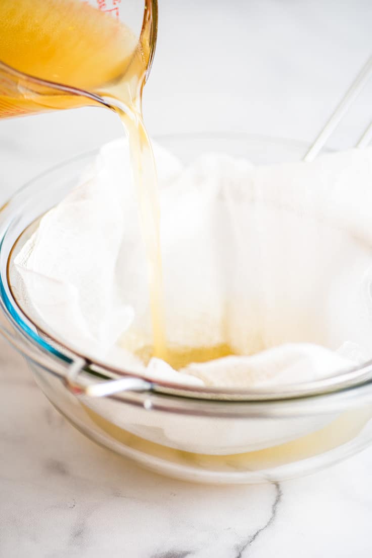 Picture of homemade chicken stock being strained through cheesecloth.