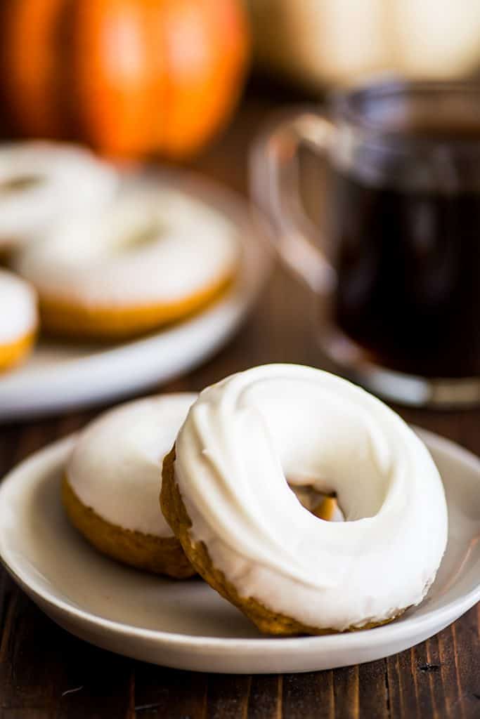Photo of two Pumpkin Donuts With Cream Cheese Glaze on a plate.