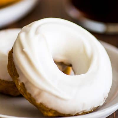Feature image of two Pumpkin Donuts With Cream Cheese Glaze on a plate.