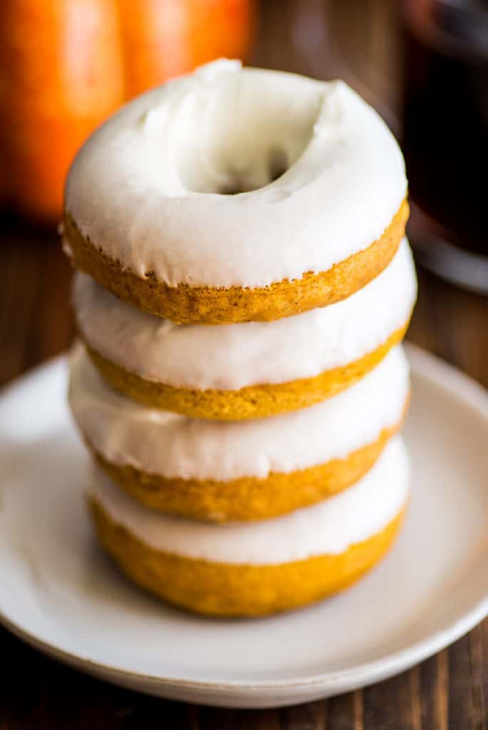 Stack of four baked pumpkin donuts with cream cheese glaze.