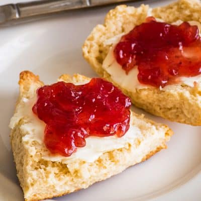 Image of small-batch cream scones cut open with butter and jelly.