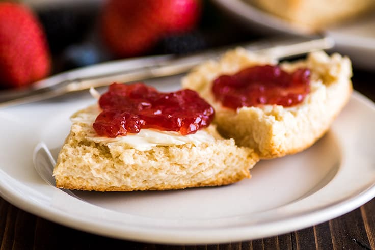 Wide image of small-batch cream scones on plate with butter and jelly.