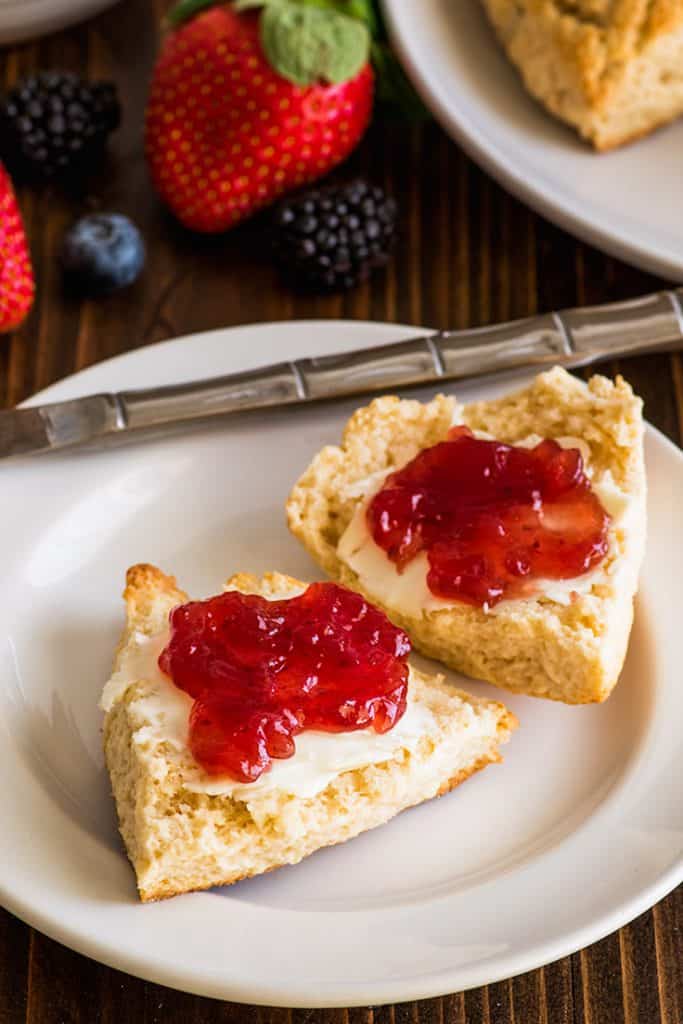 Image of small-batch cream scones cut open with butter and jelly.