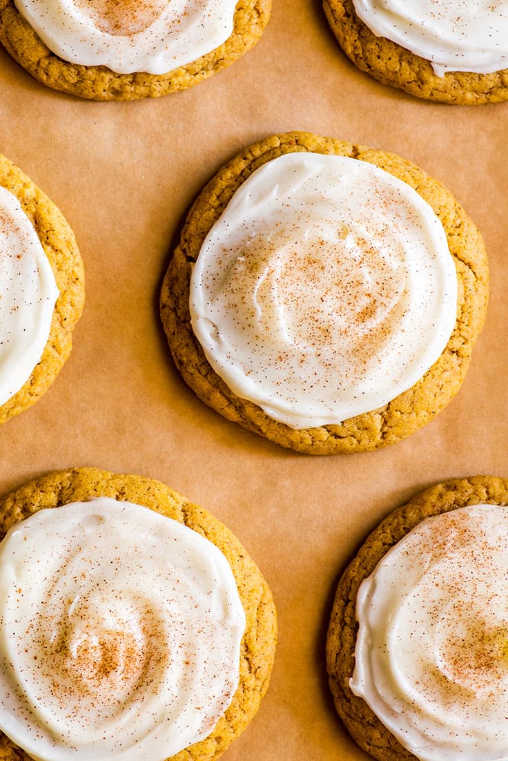 Overhead shot of Small-batch Soft Pumpkin Cookies with Cream Cheese Frosting on parchment paper.