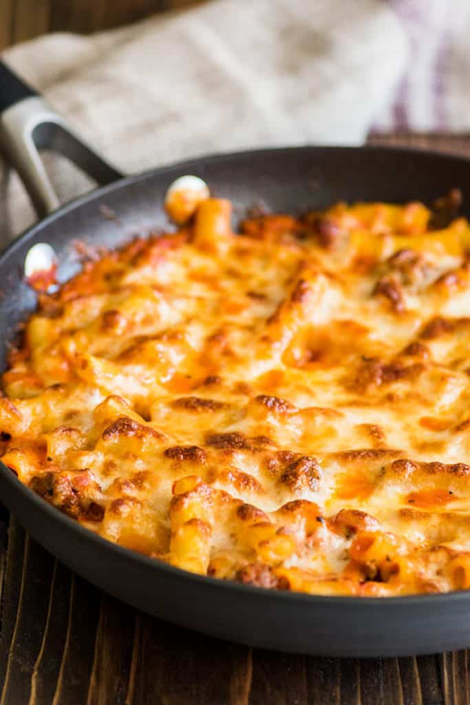 Picture of easy baked ziti in a skillet with browed cheese on top.