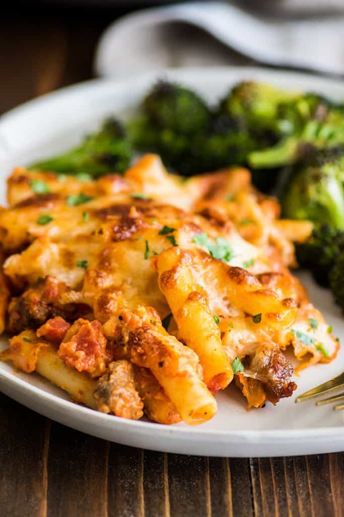 Photo of easy baked ziti on a plate with oven-roasted broccoli.
