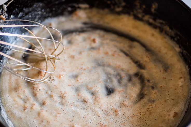 Photo of How to Make Gravy From Drippings step 3: flour being whisked into browned pan drippings.