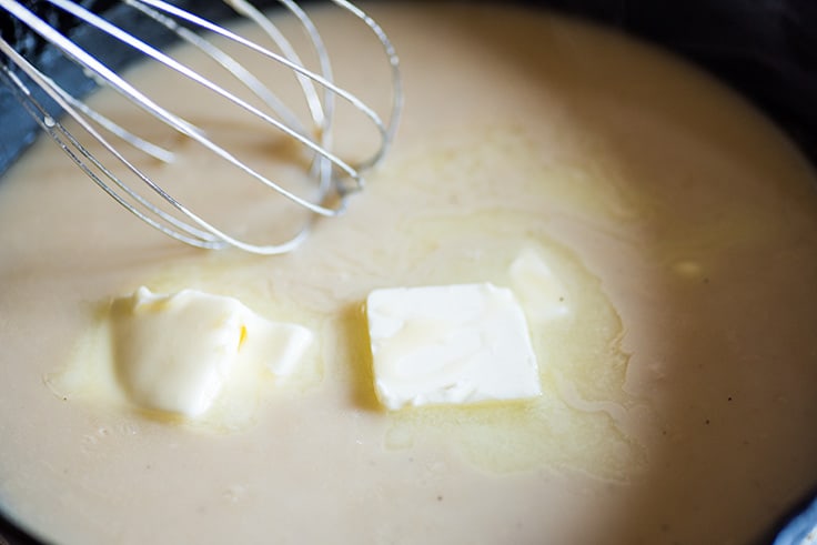 Photo of How to Make Gravy From Drippings step 5: butter being added to thickened gravy.