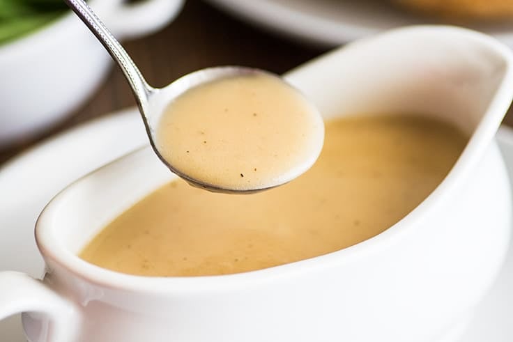 Photo of gravy made from pan drippings in a small ladle.