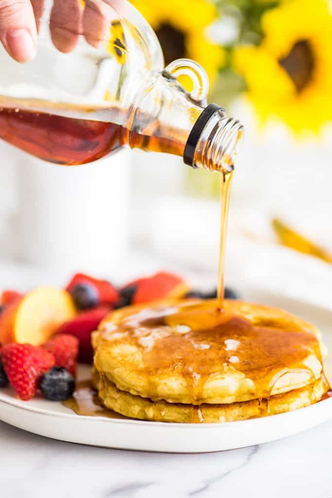 Picture of syrup being poured over two pancakes.