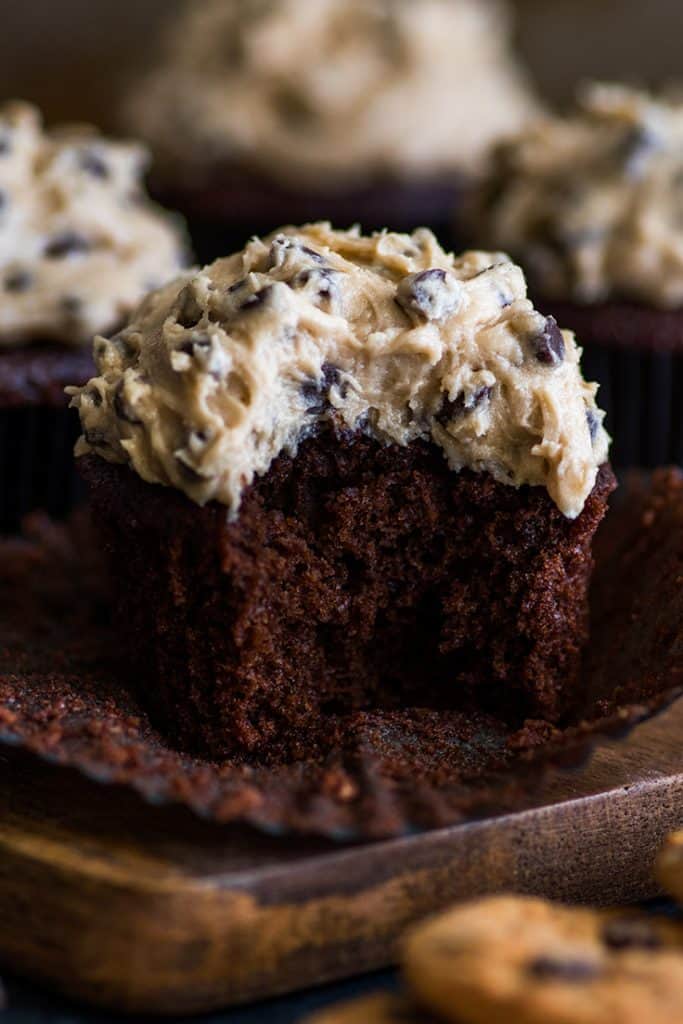 Small-batch Chocolate Cookie Dough Cupcakes are moist and decadent chocolate cupcakes smothered with a creamy, dreamy homemade cookie dough frosting. | #cookiedoughfrosting | #cupcakes | #smallbatchdessert | Photo of a Chocolate Cookie Dough Cupcake with a bite out of it.