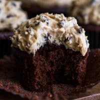 Square photo of a Chocolate Cookie Dough Cupcake with a bite out of it.