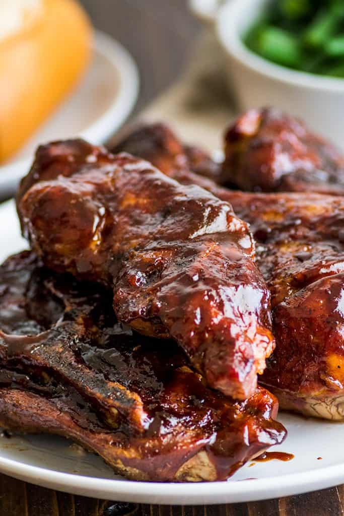 Country-style pork ribs in the oven are the perfect easy dinner. Cheap, easy to make, and SO good, this might be your new favorite way to eat pork. | cheap meals | BBQ | #summer | #summerrecipes | Photo of country-style pork ribs piled on a plate.