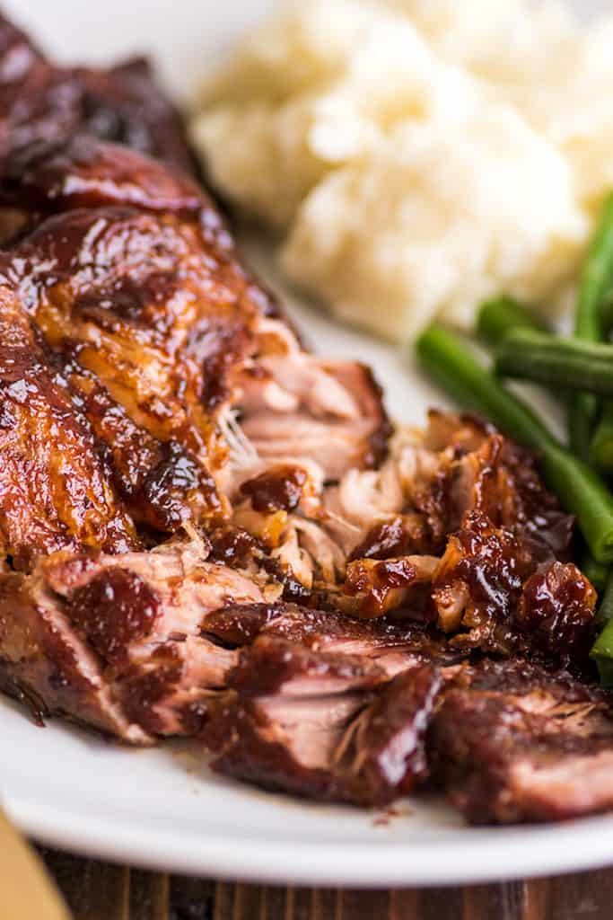 Country-style pork ribs in the oven are the perfect easy dinner. Cheap, easy to make, and SO good, this might be your new favorite way to eat pork. | cheap meals | BBQ | #summer | #summerrecipes | Shredded country-style pork rib on a plate with green beans and mashed potatoes.