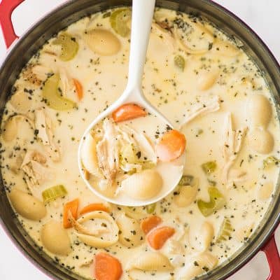 Picture of Easy Creamy Chicken Noodle Soup in a red pot being ladled.