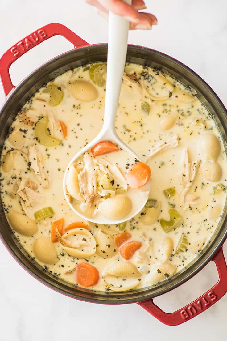 Picture of Easy Creamy Chicken Noodle Soup in a red pot being ladled.