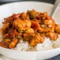 Square photo of Easy Chicken Curry over rice in a white bowl.
