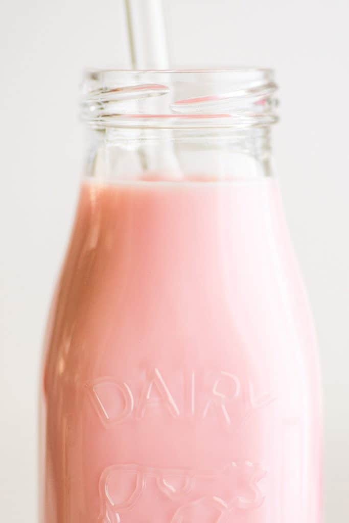 Close up image of easy homemade strawberry milk in a glass jar.