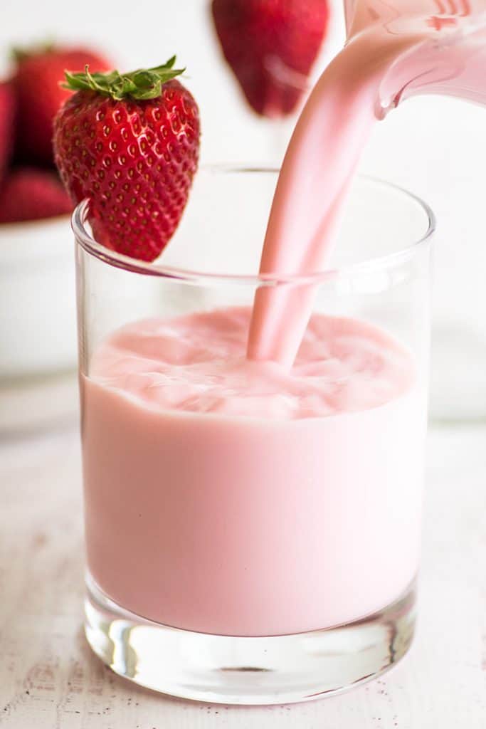 Photo of homemade strawberry milk being poured into a glass.