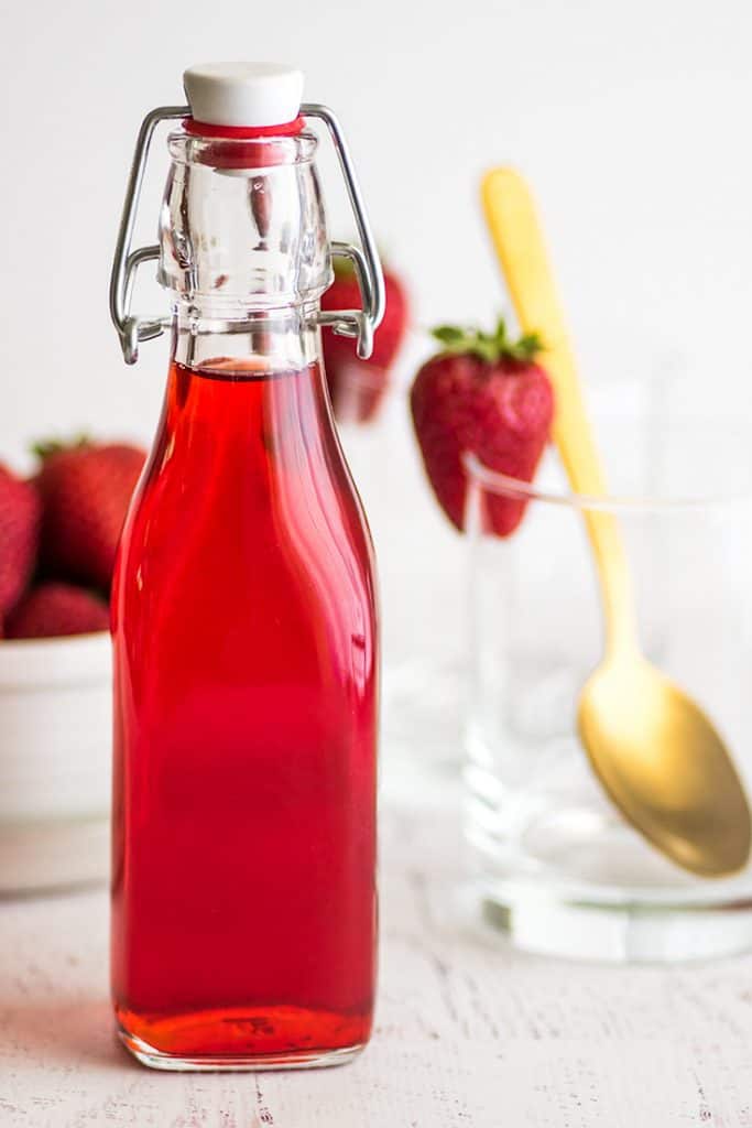 Photo of strawberry syrup for homemade strawberry milk recipe in a glass jar.