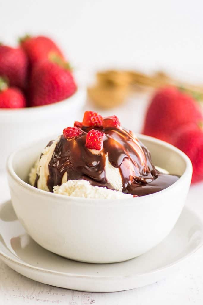 This Nutella sauce is so easy to make! Two ingredients, 30 seconds, and perfect for drizzling over ice cream, pancakes, and waffles. | #summerdessert | #Nutella | #recipeforone | recipes for one | Photo of Nutella sauce over ice cream with strawberries on top.