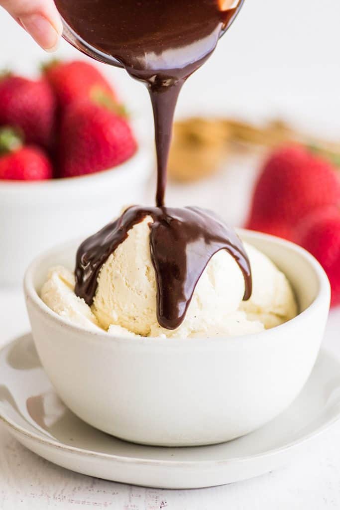 This Nutella sauce is so easy to make! Two ingredients, 30 seconds, and perfect for drizzling over ice cream, pancakes, and waffles. | #summerdessert | #Nutella | #recipeforone | recipes for one | Nutella sauce being poured over ice cream in a white bowl.