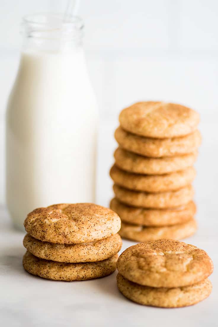 Photo of Snickerdoodle Cookies stacked next to a class of milk.