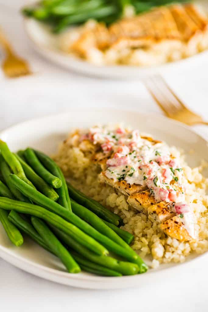 Picture of Keto Chicken in Cream Sauce on a plate over cauliflower rice next to green beans.