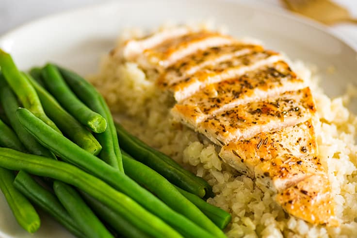 Photo of Keto Chicken on cauliflower rice next to green beans.