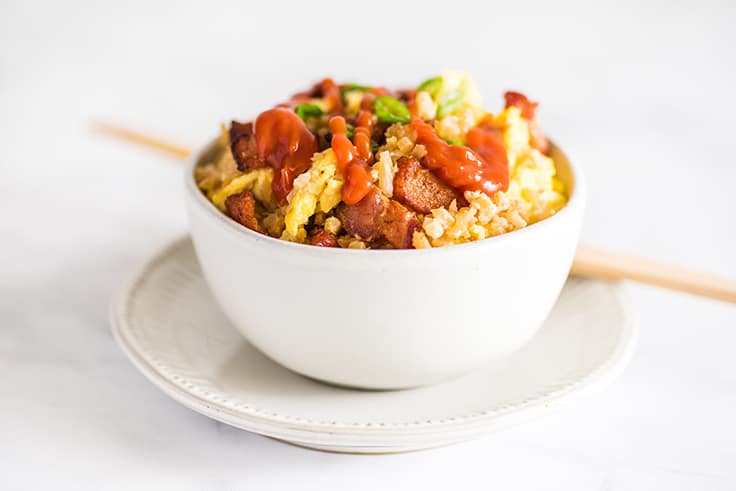 Picture of keto fried rice in a white bowl with ketchup on top.